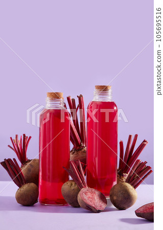 Against the pastel background, several fresh beetroots and two beetroot juice bottles without label are arranged. Beetroot (Beta vulgaris) may improve digestive health Against the pastel background, several fresh beetroots and two beetroot juice bottles without label are arranged. Beetroot (Beta vulgaris) may improve digestive health 105695516