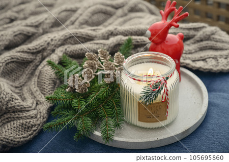 Red ceramic deer and candle in jar with fir tree branches Red ceramic deer and candle in jar with fir tree branches 105695860