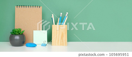 School equipment on white table, green wall background. Education backdrop. Wooden school supplies, notepad, pencils and cactus plant. Back to school. Student Desk. Stationery for study. Work at home School equipment on white table, green wall background. Education backdrop. Wooden school supplies, notepad, pencils and cactus plant. Back to school. Student Desk. Stationery for study. Work at home 105695951
