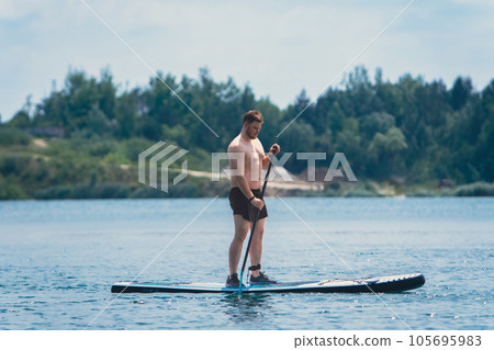 man standing on the supboard on the middle of the lake man standing on the supboard on the middle of the lake 105695983