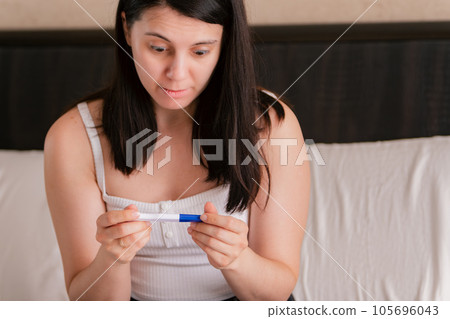 worried woman with positive pregnancy test worried woman with positive pregnancy test 105696043