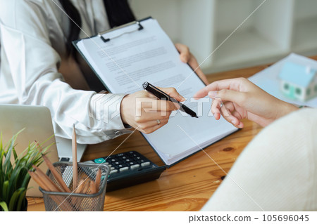 Real estate broker agent presenting and consult to customer to decision making sign insurance form agreement, home model, concerning mortgage loan offer for and house insurance. 105696045