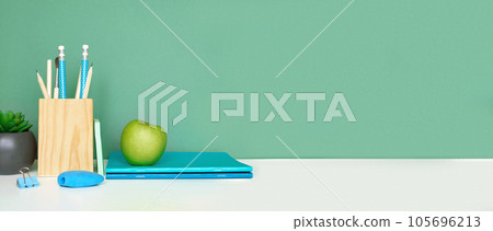 School equipment on white table, green wall background. Education backdrop. Wooden school supplies, notepad, pencils and cactus plant. Back to school. Student Desk. Stationery for study. Work at home School equipment on white table, green wall background. Education backdrop. Wooden school supplies, notepad, pencils and cactus plant. Back to school. Student Desk. Stationery for study. Work at home 105696213
