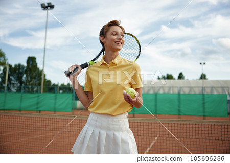 Young woman tennis player in trendy fashion sportswear posing with racket 105696286
