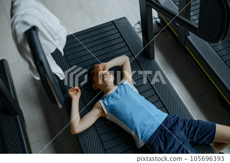 Tired exhausted boy rest lying on treadmill after hard practice Tired exhausted boy rest lying on treadmill after hard practice 105696393