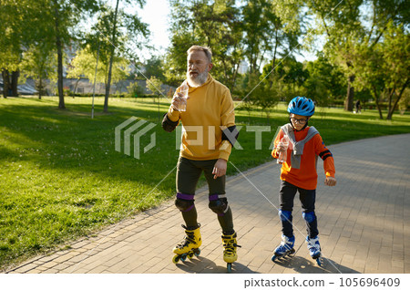 Happy senior man and little boy rollerskating in urban park Happy senior man and little boy rollerskating in urban park 105696409