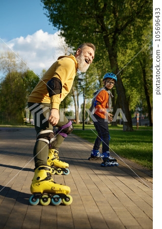 Happy grandfather and grandson on roller skates posing for camera Happy grandfather and grandson on roller skates posing for camera 105696433