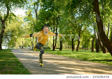 Overjoyed emotional old senior man doing trick while rising roller skates Overjoyed emotional old senior man doing trick while rising roller skates 105696438