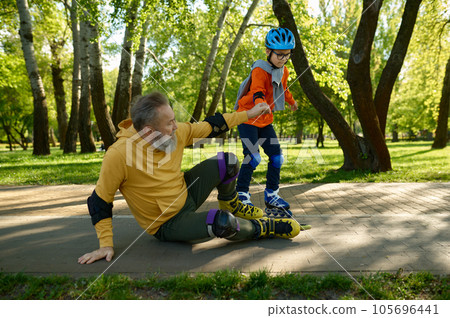 Little boy teaching old grandfather roller skating in park Little boy teaching old grandfather roller skating in park 105696441
