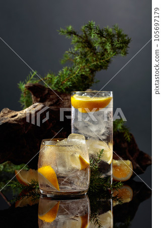 Cocktail gin-tonic with ice and lemon on a black reflective background. 105697179