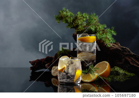 Cocktail gin-tonic with ice and lemon on a black reflective background. 105697180