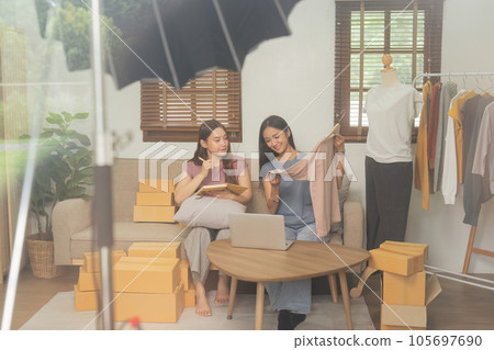 Startup small business owner working with computer at workplace. Freelance two woman seller check product order. Online selling. E-commerce. Behind the scene concept Startup small business owner working with computer at workplace. Freelance two woman seller check product order. Online selling. E-commerce. Behind the scene concept 105697690
