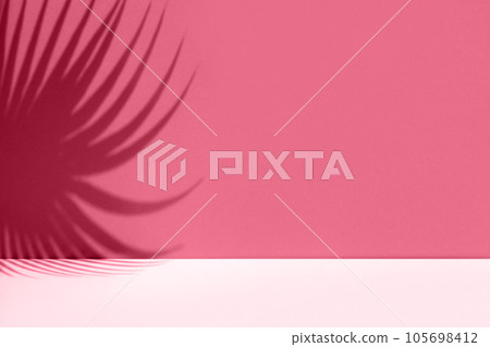 Minimal abstract background with shadow of tropical palm leaves. Presentation of cosmetic product. Premium podium. Viva Magenta colored wall and white table. Showcase, display case, Front view. Mockup 105698412