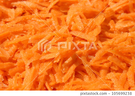 Carrots, grated on a large grater. Food orange background. 105699238