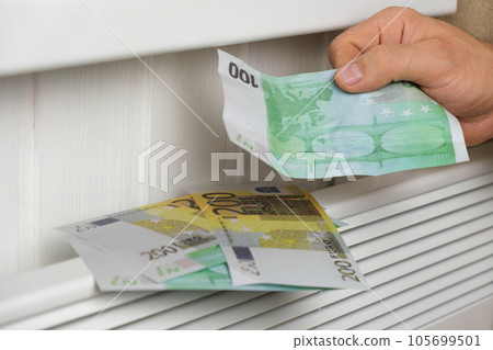 Human Hand Holding Euro Banknotes near Electric Heater Radiator at Home. Man Pay Money for Heating. Expensive to Heat. Energy Saving. Rising Cost of Living. Global Gas Crisis. Paying Cold Season Bills Human Hand Holding Euro Banknotes near Electric Heater Radiator at Home. Man Pay Money for Heating. Expensive to Heat. Energy Saving. Rising Cost of Living. Global Gas Crisis. Paying Cold Season Bills 105699501