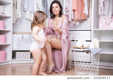 Beautiful brunette smiles little daughter two years who came bright dressing room when her mother. Beautiful brunette smiles little daughter two years who came bright dressing room when her mother. 105699517
