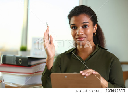 A businesswoman holds a hand up with a pen A businesswoman holds a hand up with a pen 105699855