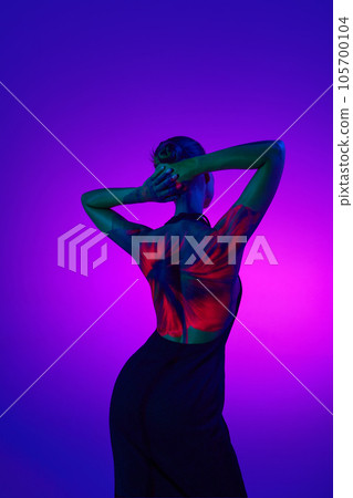 Blossom lady. Young sensual woman in digital neon filter lights showing red flower on back over gradient purple background. Blossom lady. Young sensual woman in digital neon filter lights showing red flower on back over gradient purple background. 105700104