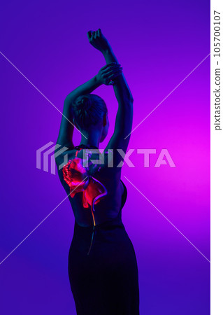 Sensual female silhouette in digital neon filter lights showing red flower on back over gradient purple background. Back view. 105700107