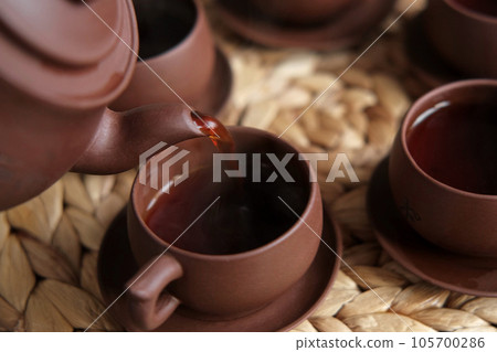 Tea Ceremony. Traditional Asian Tea Utensil, Serving Authentic Set. Person Pouring Tea from Brown Pottery Teapot to Teacup. Bamboo Tray. Lifestyle. Wellness Balance Health. Tea Brewing Equipment 105700286