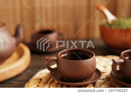 Tea Ceremony. Traditional Asian Tea Utensil, Serving Authentic Set. Person Pouring Tea from Brown Pottery Teapot to Teacup. Bamboo Tray. Lifestyle. Wellness Balance Health. Tea Brewing Equipment 105700287
