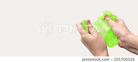 Hand Playing with textured slime on white background. Teen hand holding green shining slime with bubbles, stretching gooey substance. Teenage Girl squeezing slime toy to the sides. Liquid toy. Handgum 105700326