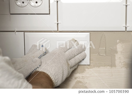 Male Worker Master Laying Ceramic Tiles on the Wall of Kitchen. Repairman Placing White Modern Tiles, Spreading Adhesive. Builder Installing Tile at Repair Renovation Work. Professional Tiling. 4K Male Worker Master Laying Ceramic Tiles on the Wall of Kitchen. Repairman Placing White Modern Tiles, Spreading Adhesive. Builder Installing Tile at Repair Renovation Work. Professional Tiling. 4K 105700390