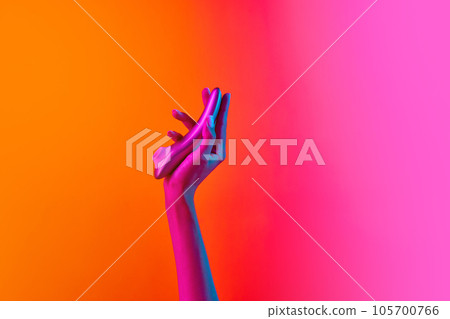 Woman's hand holding vibrator, massager over yellow-pink background in neon light. Concept of toys for adult, healthy lifestyle 105700766