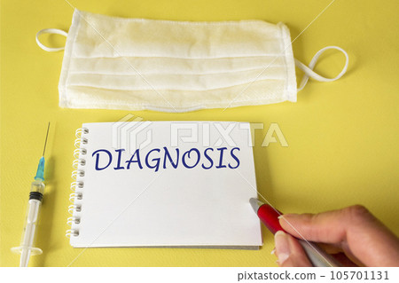 A woman's hand writes the word DIAGNOSIS on a notebook. On a yellow background lies a vaccine A woman's hand writes the word DIAGNOSIS on a notebook. On a yellow background lies a vaccine 105701131