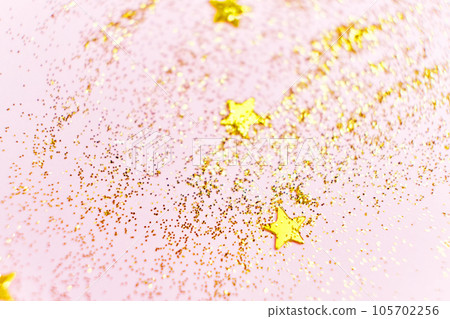 Golden glitter sequins and stars on a pink background. Golden glitter sequins and stars on a pink background. 105702256