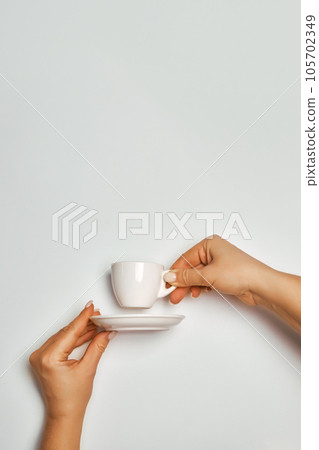 Female hands holding a white coffee cup and saucer on a white background, concept Female hands holding a white coffee cup and saucer on a white background, concept 105702349