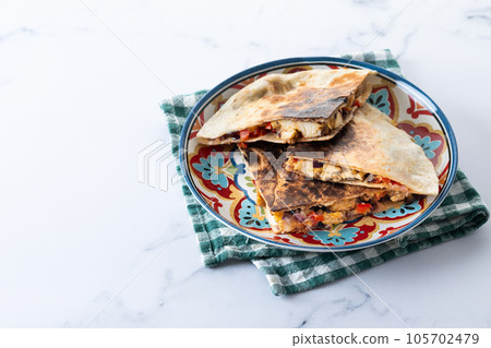 Mexican quesadilla with chicken, cheese and peppers isolated on white background Mexican quesadilla with chicken, cheese and peppers isolated on white background 105702479