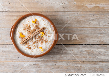 Arroz con leche. Rice pudding with cinnamon in clay bowl on wooden table Arroz con leche. Rice pudding with cinnamon in clay bowl on wooden table 105702480