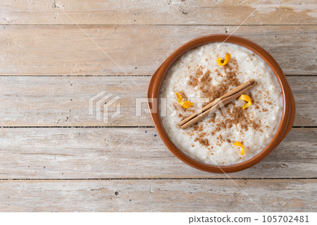 Arroz con leche. Rice pudding with cinnamon in clay bowl on wooden table Arroz con leche. Rice pudding with cinnamon in clay bowl on wooden table 105702481
