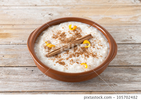 Arroz con leche. Rice pudding with cinnamon in clay bowl on wooden table Arroz con leche. Rice pudding with cinnamon in clay bowl on wooden table 105702482