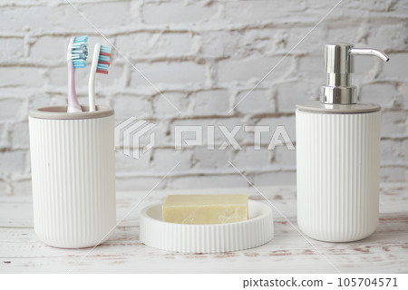 colorful toothbrushes in white mug soap and hand sanitizer on desk colorful toothbrushes in white mug soap and hand sanitizer on desk 105704571