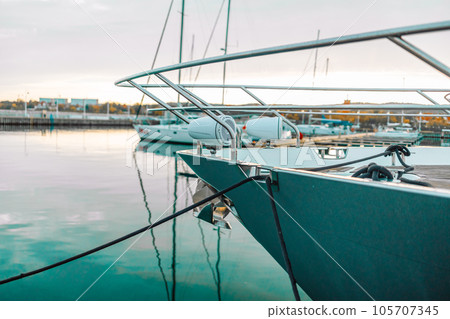 Elegant and modern sailboats moored to a pier in a yacht marina at sunset. Dramatic clouds. Poland. Transportation, sport, sailing, recreation, leisure activity, cruise, tourism. 105707345