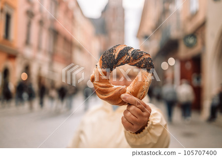 Senior woman holding prezel, traditional polish snack on the Market square in Krakow Senior woman holding prezel, traditional polish snack on the Market square in Krakow 105707400