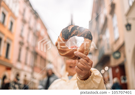 Senior woman holding prezel, traditional polish snack on the Market square in Krakow Senior woman holding prezel, traditional polish snack on the Market square in Krakow 105707401