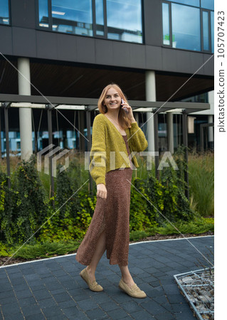 Portrait smiling young Caucasian beautiful woman sitting outside in city looking at mobile phone Portrait smiling young Caucasian beautiful woman sitting outside in city looking at mobile phone 105707423