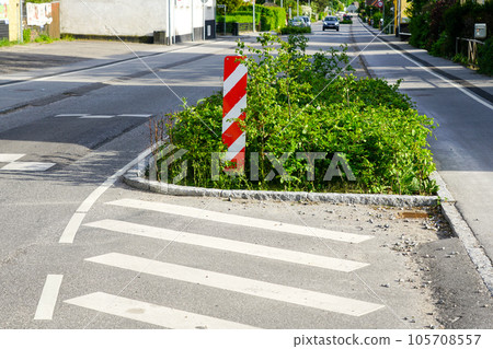 Greenery on the edge of street for forced speed reduction in the city with vertical warning sign Greenery on the edge of street for forced speed reduction in the city with vertical warning sign 105708557
