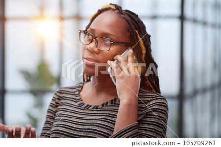 Close-up portrait of a black employee in glasses talking on the phone Close-up portrait of a black employee in glasses talking on the phone 105709261