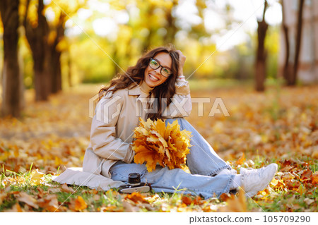 Beautiful woman taking pictures in autumn forest. Woman enjoying autumn weather. Lifestyle concept. 105709290