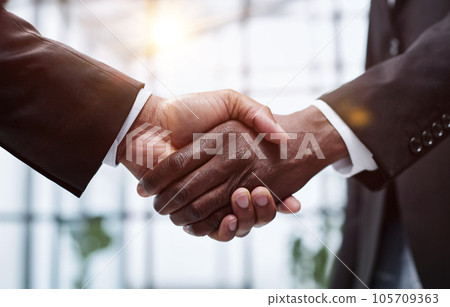 Businessmen reach out to each other to shake hands Businessmen reach out to each other to shake hands 105709363
