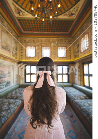a beautiful girl in a dress with a back and a bow on her head poses in a room with a traditional Turkish interior a beautiful girl in a dress with a back and a bow on her head poses in a room with a traditional Turkish interior 105709446