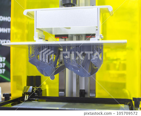 Printed models on 3D printer close-up. Objects printed on photopolymer sla 3D printer from liquid photopolymer resins on printing platform inside 3d printer. Modern progressive additive technology. Printed models on 3D printer close-up. Objects printed on photopolymer sla 3D printer from liquid photopolymer resins on printing platform inside 3d printer. Modern progressive additive technology. 105709572