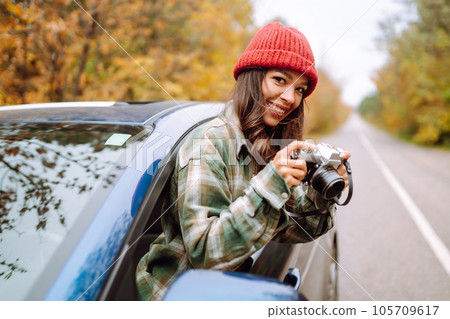 Beautiful woman takes pictures on camera from the car window. Rest, relaxation, lifestyle concept. Beautiful woman takes pictures on camera from the car window. Rest, relaxation, lifestyle concept. 105709617
