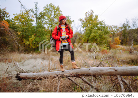 Beautiful woman taking pictures in autumn forest. Smiling woman enjoying autumn weather. Lifestyle 105709643