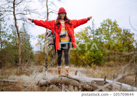 Beautiful woman taking pictures in autumn forest. Smiling woman enjoying autumn weather. Lifestyle 105709644