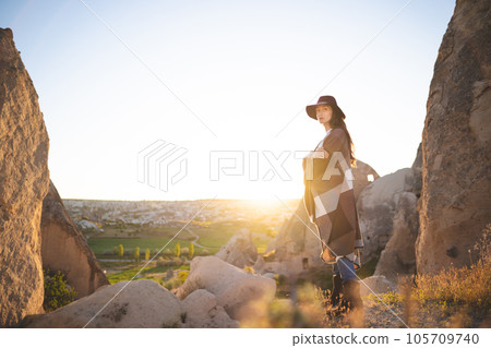 girl hiker in poncho and hat on top of mountain at sunset 105709740